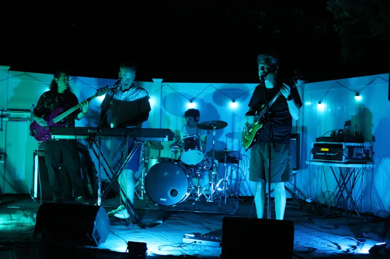 The band on stage under orange lights at the Pool Party
